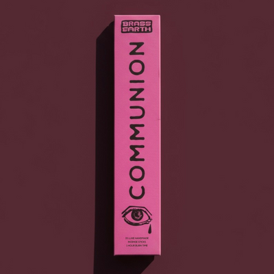 Pink box labeled 'Communion' by Brass Earth on a dark background