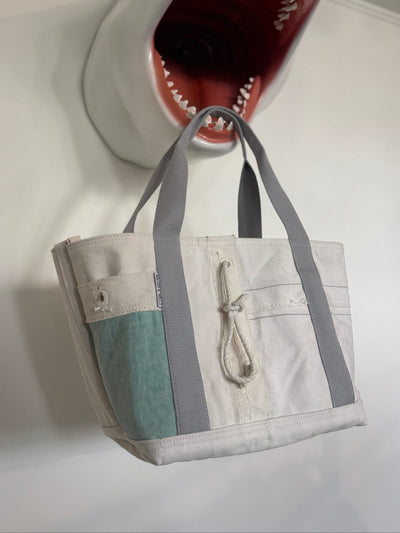 Shark-shaped wall decoration with a handbag hanging from its mouth on a white wall.