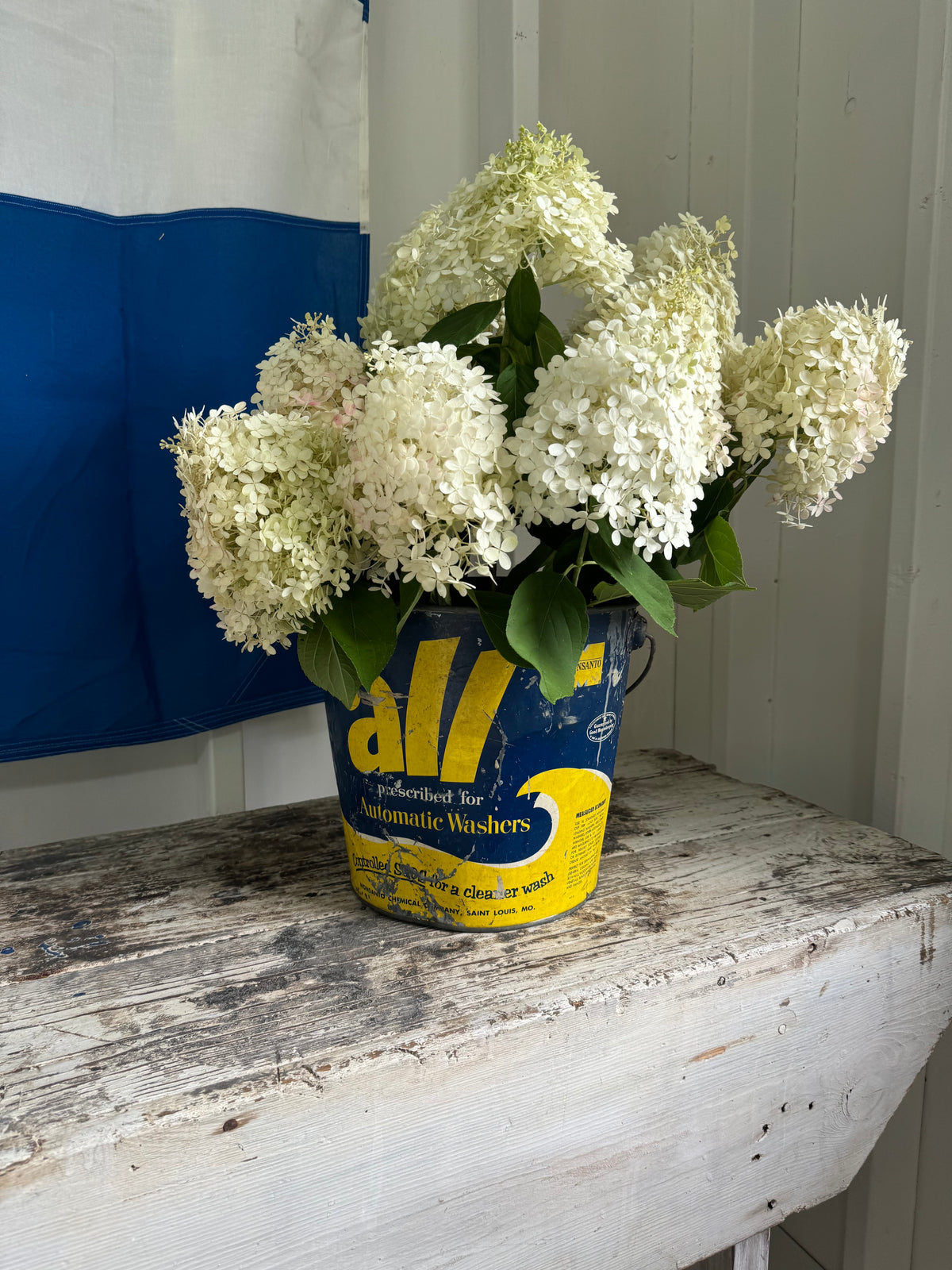 photos of a vintage workbench and a vintage laundry pail filled with hydrangeas