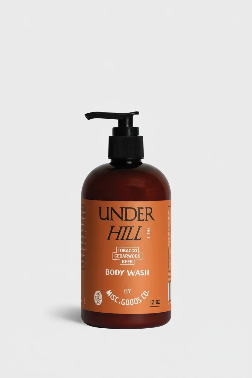 Brown bottle of Under Hill body wash with pump on a light gray background