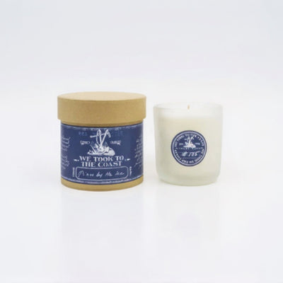 Candle with a blue label and wooden lid on a white background - we took to the coast