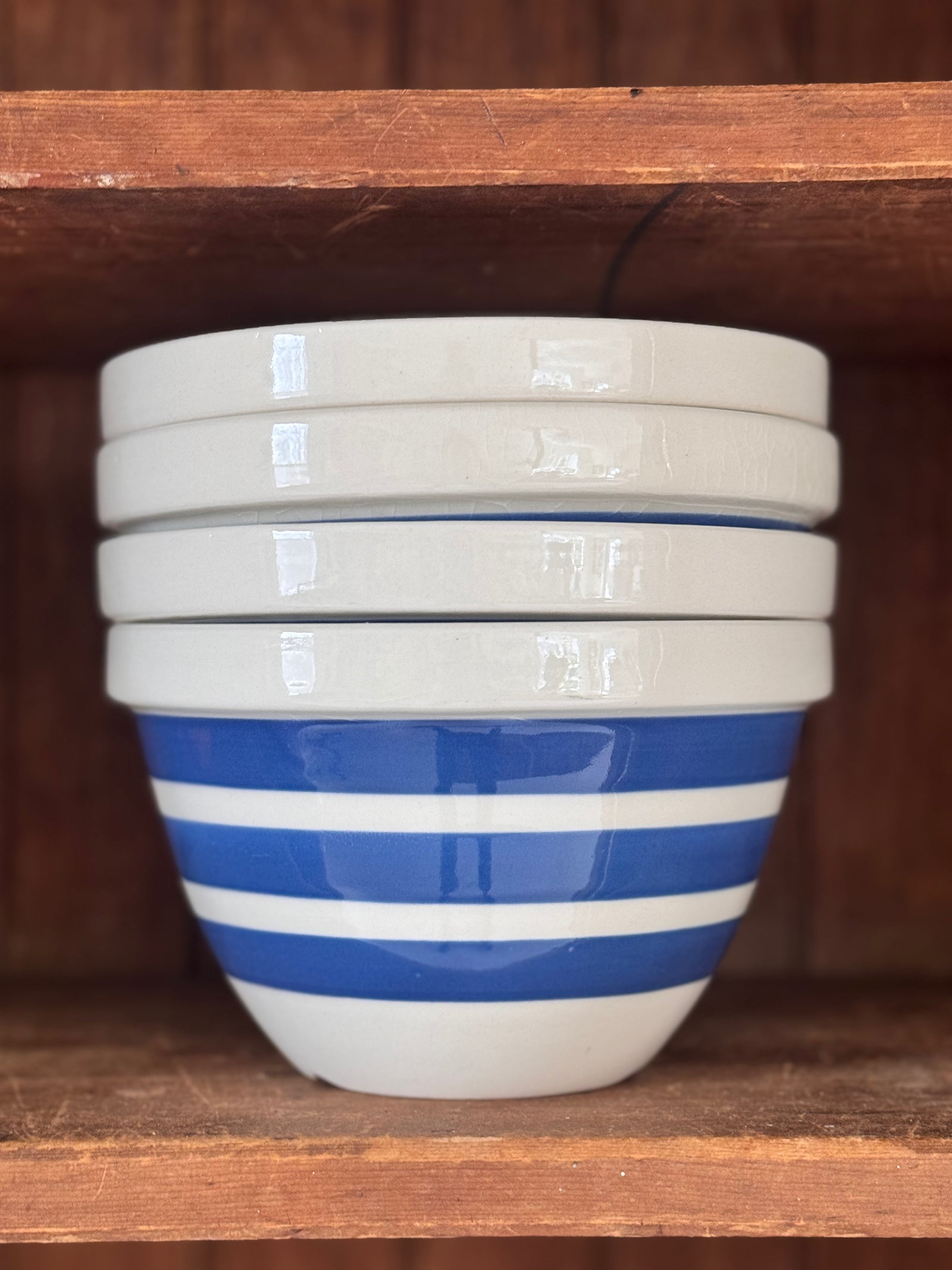 Stack of white bowls with blue stripes on a wooden shelf