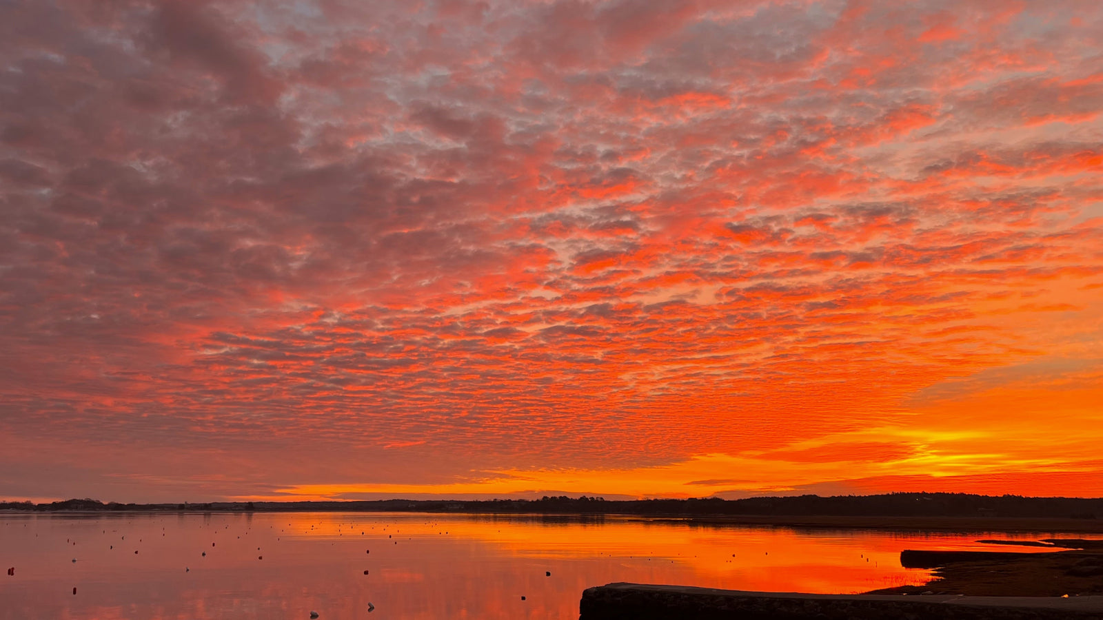Sunset over a calm body of water with orange and pink hues in the sky.