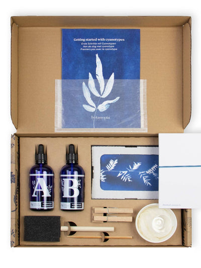 Open cardboard box containing beauty products and a blue leaf-themed card.